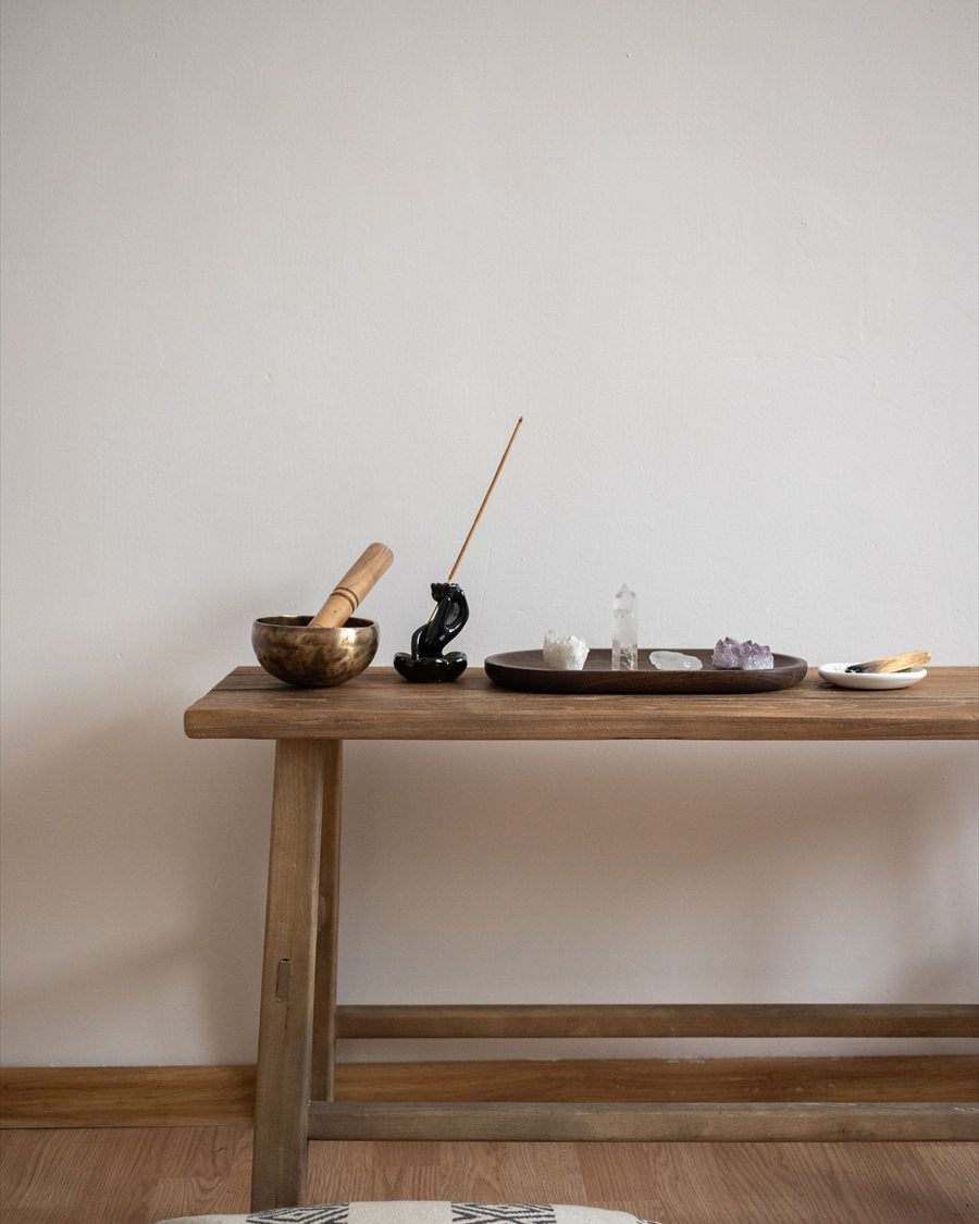 Incense, a mortar, and small crystals arranged on a simple wooden table