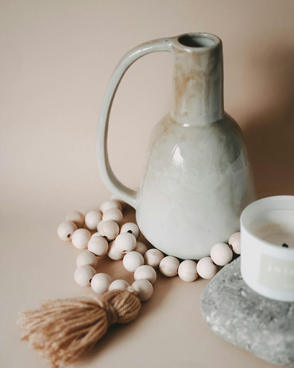 A pale strand of round wooden beads and a soft tassel in a neutral still life