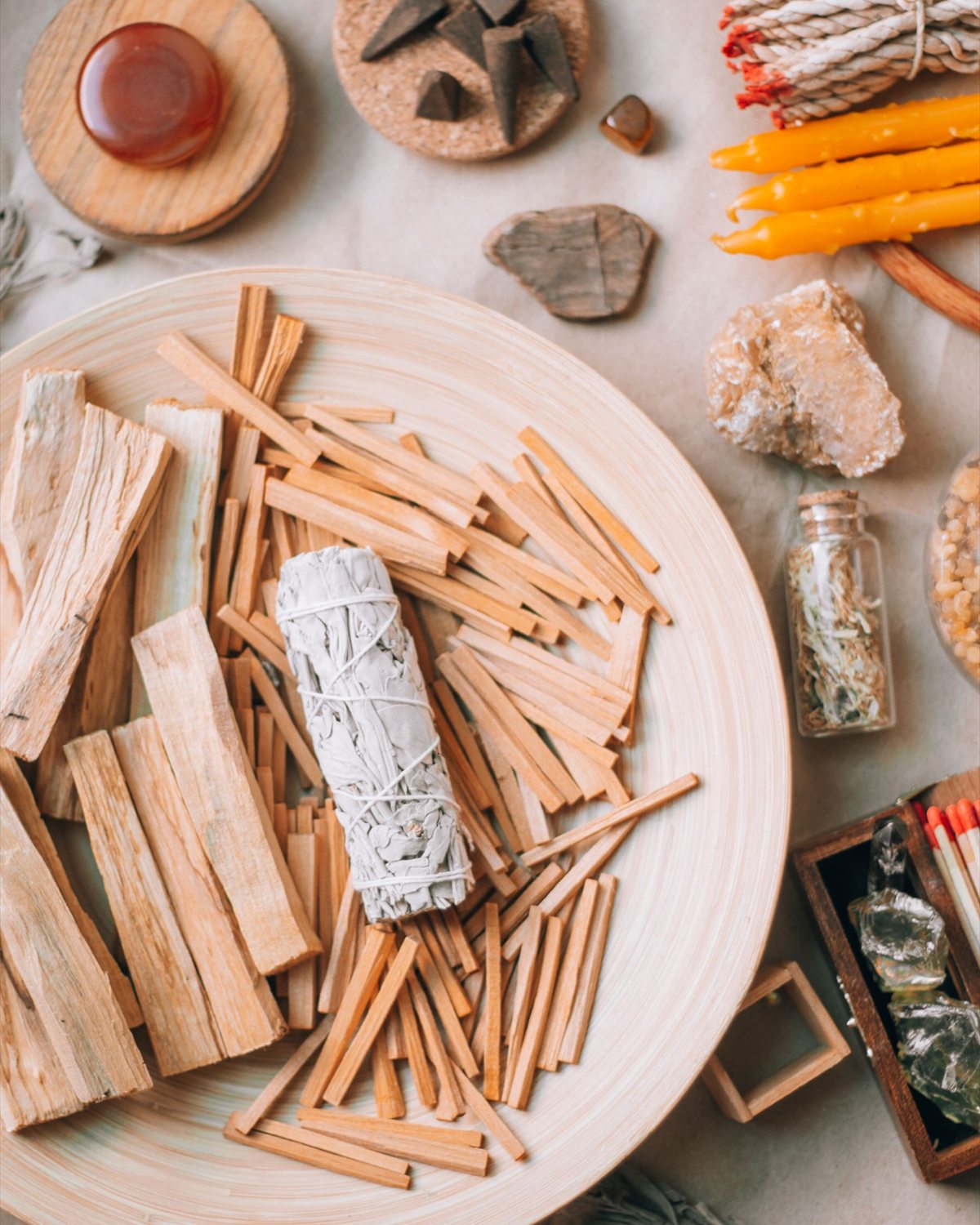 Incense wood, candles, dried botanicals, and small ritual objects arranged in warm natural light