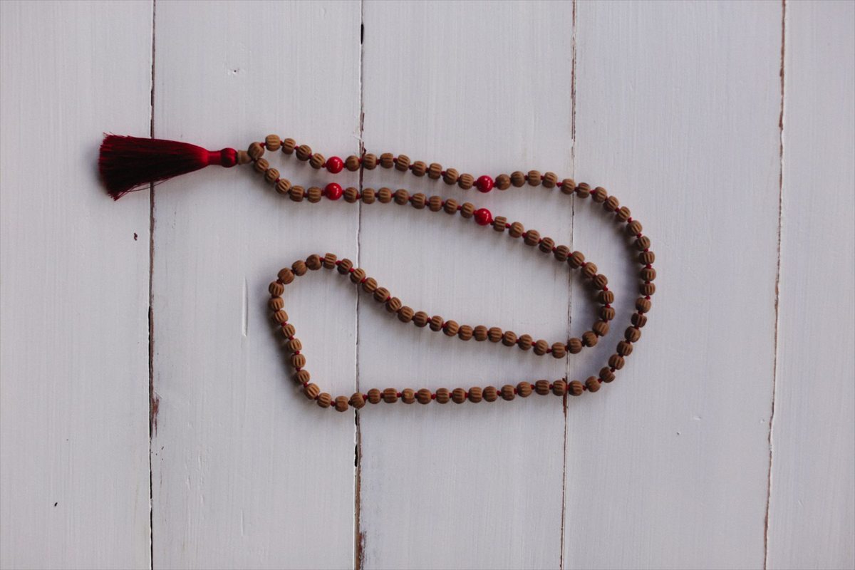 A long strand of brown and red prayer beads laid on white wood